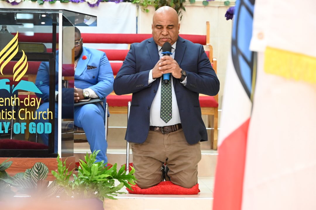 A pastor kneeling in prayer during a Sabbath service